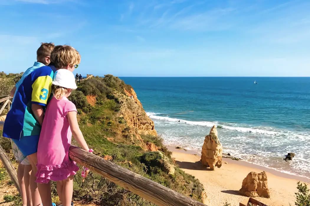 Family overlooking Algarve cliffs and a sandy beach with turquoise sea, southern Portugal